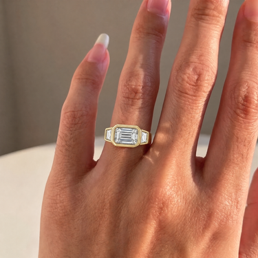 East West Emerald Cut Diamond Bezel Ring With Trapezoid Side Stones